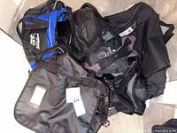 Pile of five duffel bags including black North Face and blue-black bag