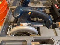 Blue and black Ryobi 14.4V circular saw inside carrying case with battery and charger visible.
