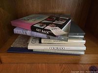 Stack of 8 coffee table books showing titles and covers including The Beatles Get Back, Italy, and Ansel Adams photography books.
