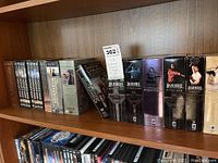 Photo showing various British TV series DVD box sets lined up on a shelf. Boxes include titles from different series with visible covers showing actors and series names.