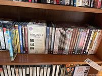 Wide view of DVD collection showing multiple titles aligned closely on shelf including boxed sets and individual DVDs