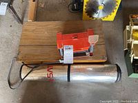 Set showing 5 red Kmart bench grinders on a wooden box with a rolled reflective car sunshield underneath.