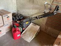 Side view of Toro Recycler mower with attached grass bag and red gasoline can placed on concrete floor