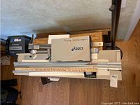 Top-down view of Logan mat cutter on wooden table with a wooden yardstick across front