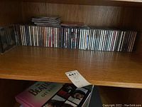 Shelf with over 40 music CDs arranged side by side revealing spines and some cover art.