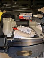 Porter-Cable nailer inside black plastic carrying case, includes nailer, nails in box, small bottle and instruction paper.