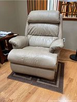 Front view of beige leather recliner chair showing padded armrests, cushioned back, and seat.