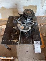 View of router mounted on metal router table showing surface condition and setup.