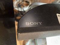 Close-up of Sony logo on the soundbar showing black fabric and plastic surface.