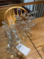 Lot of 25 assort stemware glasses arranged on wooden table showing multiple styles and sizes.