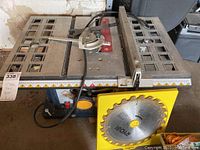 Full view of the Ryobi 10 inch table saw with miter bar and attached combo saw blade, displaying the table and measuring scale on the fence.