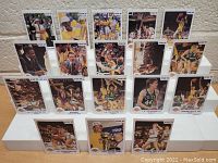 Front view of all 18 basketball cards displayed in rows showing players and scenes from 1986 NBA Finals involving Los Angeles Lakers, including Kareem Abdul-Jabbar, Magic Johnson, Larry Bird