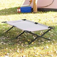 Coleman Trailhead II Extra Wide Folding Cot set up outside on grass with tent in background to show usage.