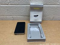 Heyday power bank in black alongside its original white box and plastic tray insert on a wooden surface with a brick wall background