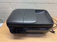 Front angle view of the HP OfficeJet 3830 printer showing the closed paper tray and the top scanning bed.