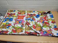 Piece of Muppet Treasure Island themed fabric showing colorful muppet characters, ropes, and treasure chests on white background.