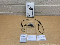 Sony WI-C310 Bluetooth headset laid out on table with box and manuals, showing the entire contents of the lot.