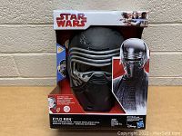 Black Kylo Ren mask displayed in its original Star Wars packaging with character image, showing mask front and details.