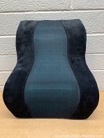 Front view of the Brookstone back cushion showing ergonomic shape with black plush sides and textured gray center.