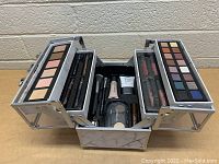Open view of ULTA Beauty makeup case revealing contents including eyeshadow palettes, lip glosses, eyebrow products, brushes, and face makeup items.
