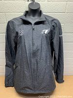 Front view of dark gray women's jacket showing Philadelphia Eagles logo on left chest, NFL shield on right chest, and Reebok logo on left sleeve.