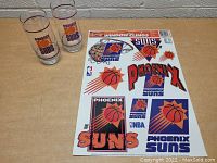 Two Phoenix Suns vintage glasses and one sheet of window clings on tabletop.