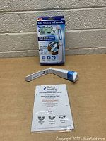 Photo showing the foldable handheld UV sanitizing light device alongside its original packaging box and instruction pamphlet on a plain table.