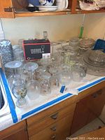 Collection of various glassware and crystal pieces on a kitchen counter, including stemmed glasses, vases, and covered crystal bowls.