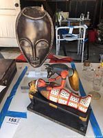 Front view of wooden African mask and colorful Egyptian Osiris figurine on table
