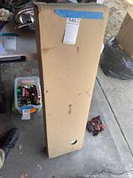 Closed cardboard box containing IKEA AVDALA shelves, with blue tape and a label showing '145'