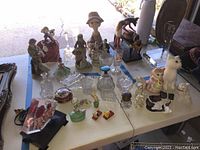 Wide view of table with multiple figurines: porcelain, crystal, wooden, and ceramic cats.