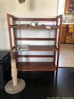 Full view of wooden small bookshelf with four shelves and loose top bar, some items placed on shelves for scale only, not included in lot