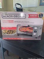 Box front showing Black+Decker Crisp n Bake Air Fry 4-Slice Toaster Oven with air fry technology, digital controls, and cooking functions.