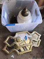 Plastic bin containing a vintage frosted hanging glass lamp with metal top, chain coiled inside the bin, and a pair of decorative carved mirror sconces resting outside the bin.