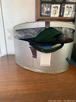 Oval vintage hat box partially opened showing item inside.