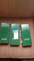 Three green Jack Taylor branded boxes for vintage ties, unopened and containing ties.