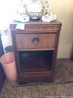 Front view of the vintage nightstand showing single drawer with metal pull, top surface, and open lower shelf.