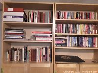 Wooden bookshelf with assorted hardcover and paperback books including gardening and landscape titles.