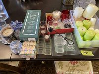 Wide view of all candle holders, boxed and loose candles on table.