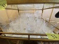 Multiple cut crystal glasses displayed on a two-tier glass shelf