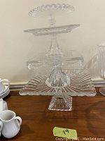 Four assorted glass and crystal cake stands arranged in a stack with various shapes and pedestal bases visible.