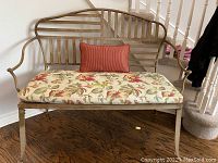 Full view of metal bench with floral cushion and lumbar pillow on hardwood floor