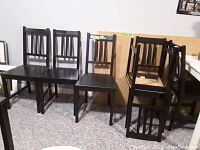 Black wooden chairs lined up against wall, showing part of the set