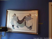 Full view of framed art print showing two figures holding patterned blanket, silver frame.