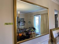 Rectangular gold-framed mirror hung on wall showing reflective surface and surroundings