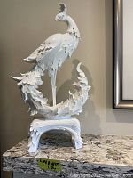 Front view of white ceramic Phoenix sculpture on marble surface