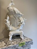 Full front view of white ceramic phoenix sculpture on tabletop