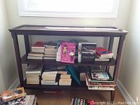 Front view of wood console table filled with books on three shelves