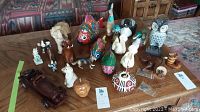 Various animal figurines including fish, birds, elephant, owl, and carved heads along with a wooden car and other small items displayed on a table.
