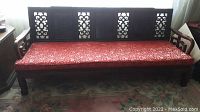 Full front view of three-seater couch showing carved back panels and red cushion